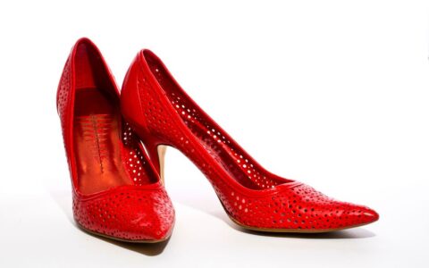 Stylish red high heel shoes with perforated design on a clean white backdrop.