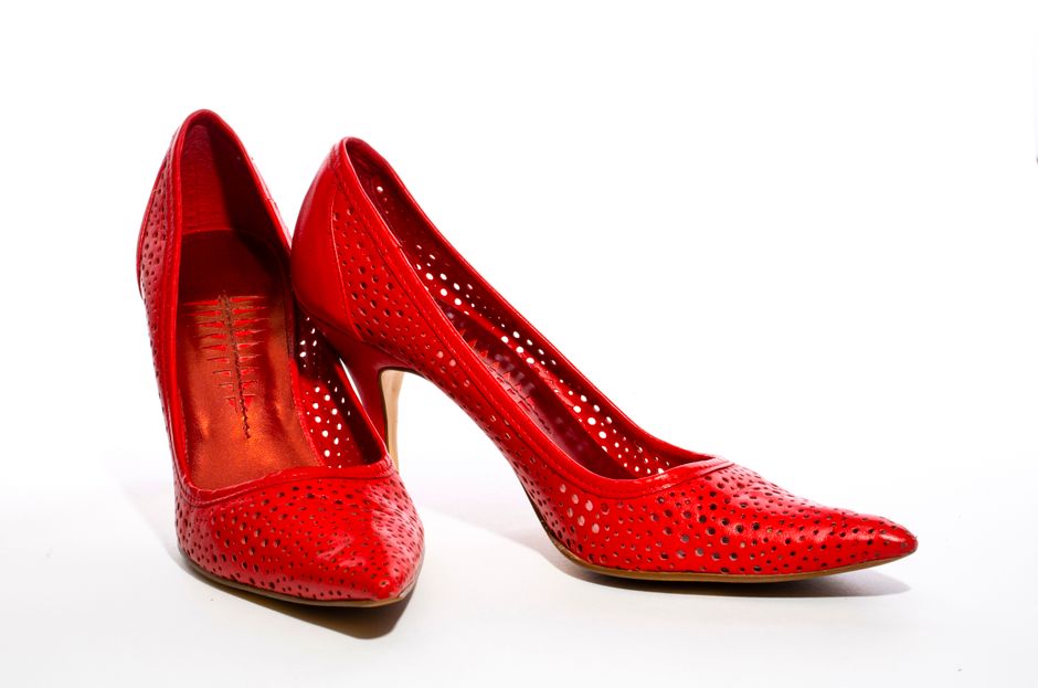 Stylish red high heel shoes with perforated design on a clean white backdrop.