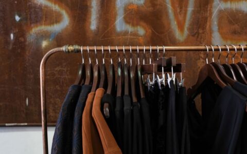 Modern clothing rack in a boutique with diverse garments and wooden hangers