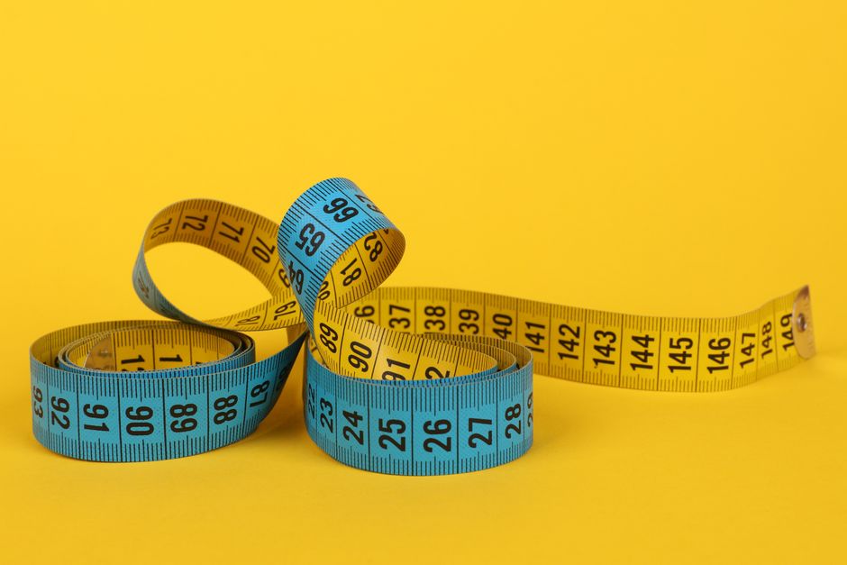 A coiled blue and yellow measuring tape on a bright yellow background.