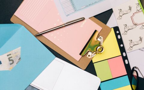 Neatly arranged desk supplies with clipboard, euro bill, and colorful notes.