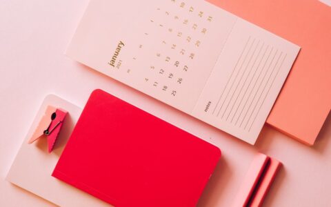 Layout of calendar paper with notes on bright multicoloured notebooks on pink background