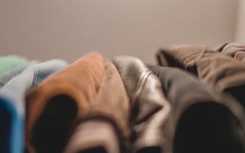 A textured close-up of colorful folded fabrics showing a variety of materials in warm lighting.