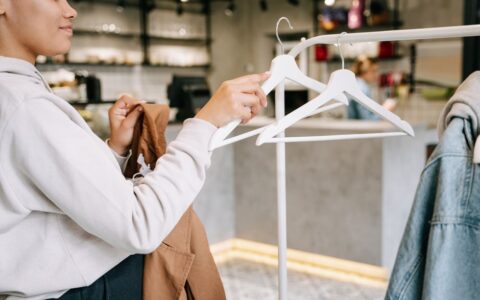 A woman browsing and selecting clothes in a modern boutique store with minimalistic interior.