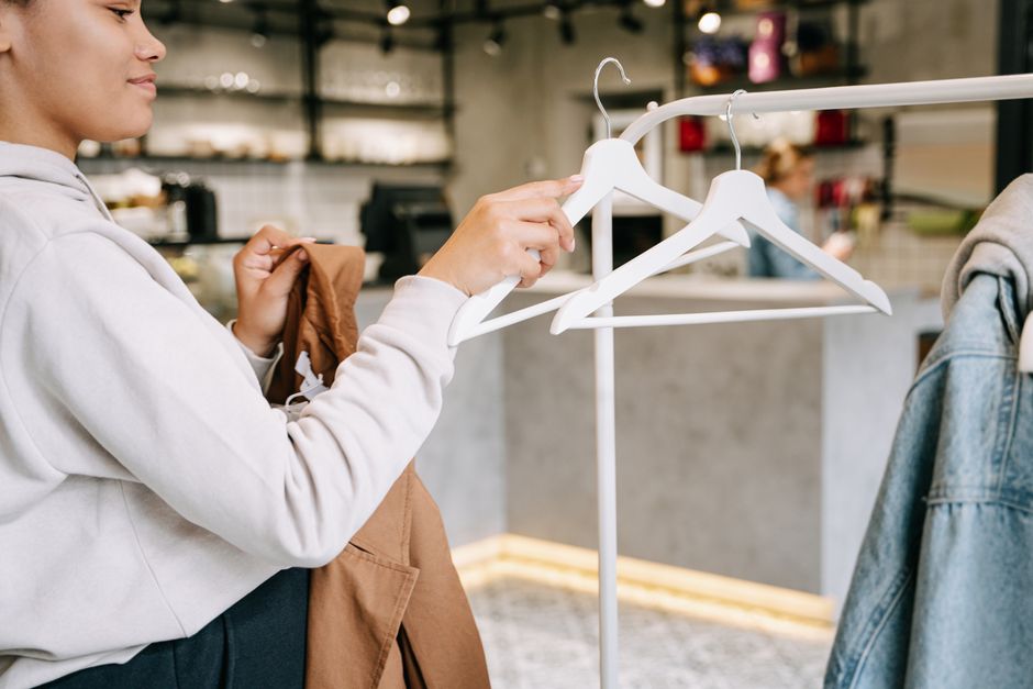 A woman browsing and selecting clothes in a modern boutique store with minimalistic interior.